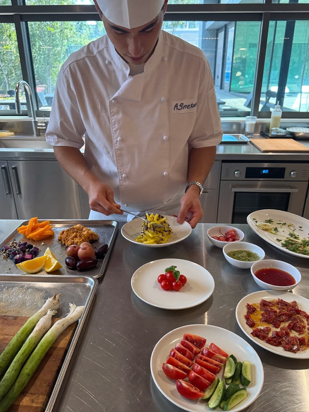 Chef plating a fresh dish in a bright, modern restaurant kitchen